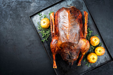 Traditional roasted stuffed Christmas goose with apples and herbs as top view on a rustic metal tray with copy space left - obrazy, fototapety, plakaty