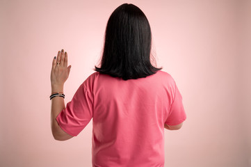 Beautiful woman doctor with stethoscope, wearing pink scrubs showing oath from behind