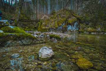 Stone structure at the river spring of Kamniska Bistrica in Slovenia in dry winter time. Cold enchanted rock with flowing water in the middle of the forest.