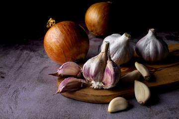 garlic bulb and cloves with onion on dark background