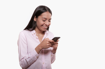 Fototapeta premium young latin girl smiling and talking on the cell phone on white background dressed in pink
