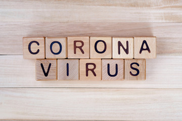 The inscription corona virus on a wooden background, top view. The epidemic of the covid-19 virus. Wooden cubes with letters.