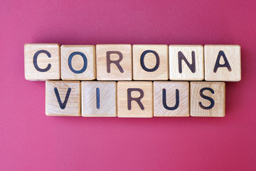 The inscription corona virus on a dark pink background, top view. The epidemic of the covid-19 virus. Wooden cubes with letters.