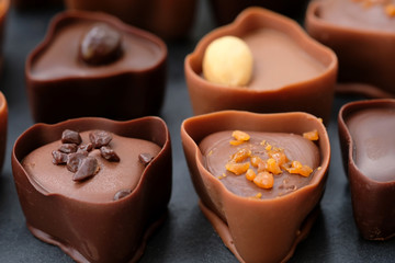 Chocolate candies with different fillings close-up. Milk and chocolate sweets with caramel, coffee and nuts. Delicious handmade chocolate desserts.