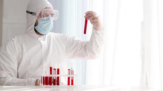 man in protective medical outfit working in laboratory with test tubes, analysing samples