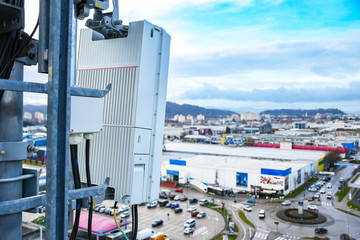 5G new radio telecommunication network antenna mounted on a metal pole providing strong signal waves from the top of the roof across big city 