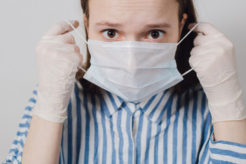 girl puts on a medical mask on a white background. corona virus prevention