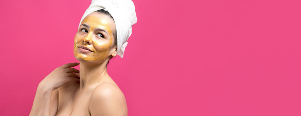 Beauty portrait of woman in white towel on head with gold nourishing mask on face. Skincare cleansing eco organic cosmetic spa relax concept.