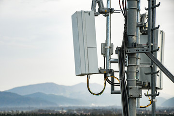5G new radio telecommunication network antenna mounted on a metal pole providing strong signal waves from the top of the roof across big city 