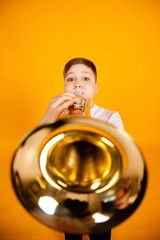 A cheerful boy plays the pipe blowing his cheeks. Humor playing a wind instrument.