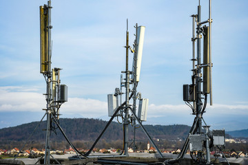 Cellular radio telecommunication network antenna mounted on a metal pole providing strong signal waves from the top of the roof across big city 