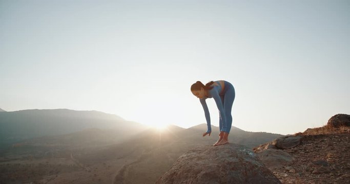 Athletic fit girl training in mountains during sunrise, doing various yoga positions in her meditation session - active lifestyle, zen concept 4k footage