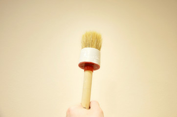 Wooden brush in the hand. The design idea of ​​repair and a new interior of an apartment or house with your own hands. Painting walls and radiators with paint.