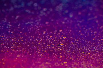 A lot of small drops of water on a colorful pastel holographic background.