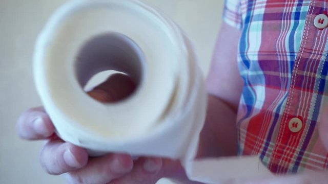 Men's hands unwind a roll of white toilet paper