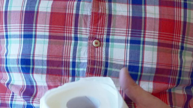 Men's hands unwind a roll of white toilet paper.
