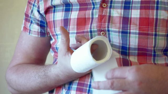 male hands hold a roll of white toilet paper.