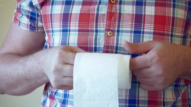 male hands hold a roll of white toilet paper.