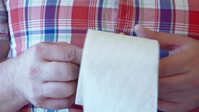 male hands hold a roll of white toilet paper