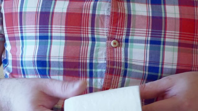 male hands hold a roll of white toilet paper.