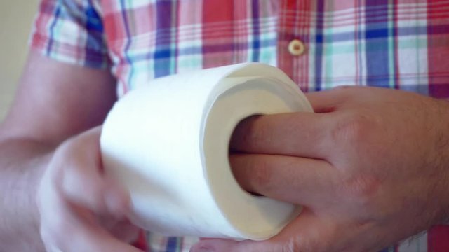 male hands hold a roll of white toilet paper.