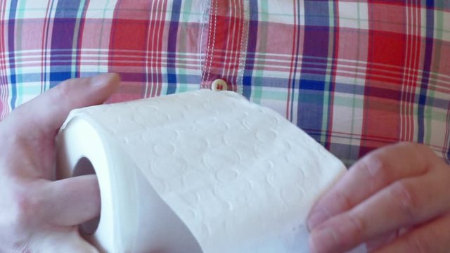 Men's hands unwind a roll of white toilet paper