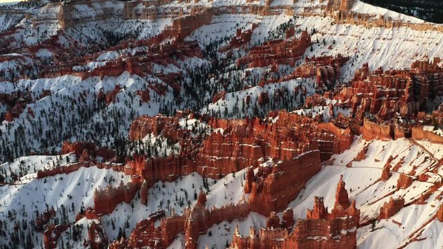 Beautiful morning aerial drone view of the famous Cathedral in Bryce Canyon National Park, Utah. Gorgeous natural red rocks in pillar formations with white snow covering them creating contrast.
