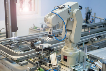 Industry 4.0 smart factory concept; artificial intelligence in production. Robot arm picks up the product from automated car. Selective focus.