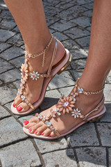 Close-up of a few feet with beautiful sandals with rhinestones and red manicure
