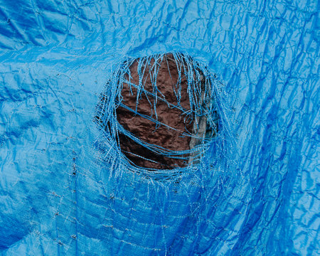 Close up worn blue tarp with tattered hole in center,Fishing Nets