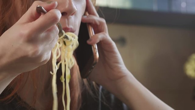 Attractive Redhead Girl Eats Instant Noodles Raft Mac And Cheese In The Kitchen. Eats Junk Food. Bad Lifestyle. Talking On The Phone. Food On The Go. Brewed Yellow Ramen In A Special Plastic Plate.