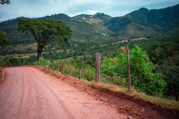 Fototapeta na wymiar Camino rural rojo en medio de la montaña