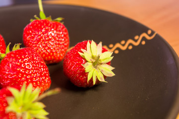 fresh ripe berries strawberries on black ceramic plate, close up