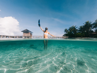 Obraz na płótnie Canvas Caucasian traveller in snorkel mask feeling happiness and freedom during tropical vacations on Indonesian island with palm trees and crystal water for exploring ocean shallow, holidays on Raja Ampat
