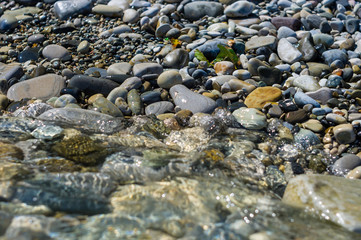 pebble stones on the sea beach, the rolling waves of the sea with foam