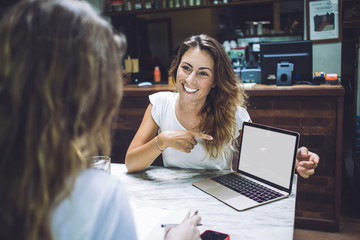 Cheerful beautiful female laughing and pointing on laptop