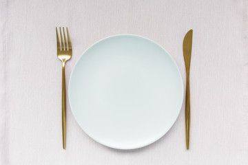Golden cutlery and plate on a pink background . Holiday cooking, meal, celebration and food concept. Top view, flat lay, copy space