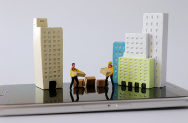 Miniature houses and miniature couriers on top of smartphones.