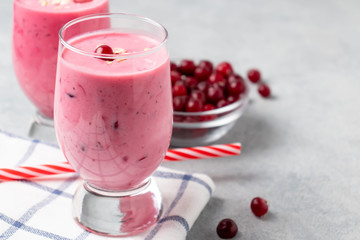 Two glasses with freshly homemade smoothie of yogurt, oatmeal and cranberries on a gray table. Healthy eating concept