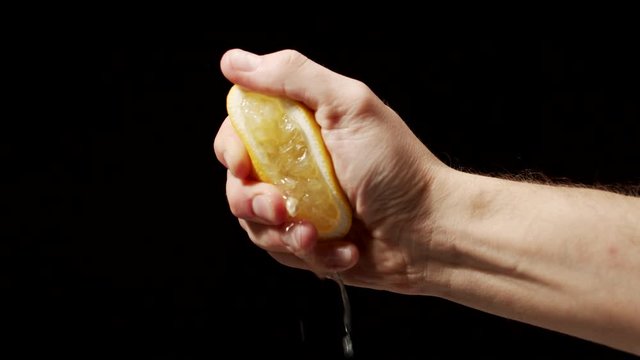 Male chef hand squeeze lemon as juice pors down 