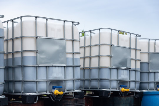 white ibc container in outdoor stock yard of factory, white plastic chemical tanks.