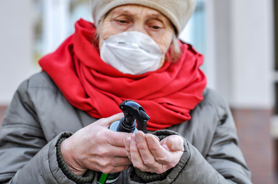 An elderly woman in a respirator handles her hands with a sanitizer antiseptic against coronavirus. COVID-2019 Senior Health. Old woman in a protective mask