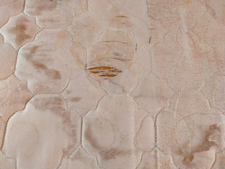 The old corrugated mattress texture. There are dirty stains. And there is a hole that was damaged, able to see material inside.