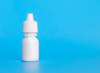 Eye drop bottle, plain, 20 ml. Single white small plastic dropper bottle. With plastic screw top. Used to dispense and store liquids. For medical treatment. Soft blue background. Copy space