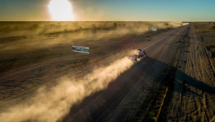 Four wheel drives cross the SA/QLD border at sunset on the Birdsville Track