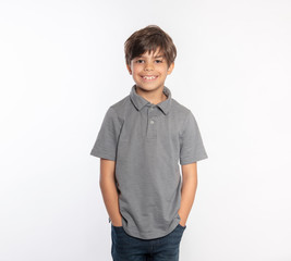 Cute standing young boy in gray polo shirt hands in pockets isolated on white background - 331105447
