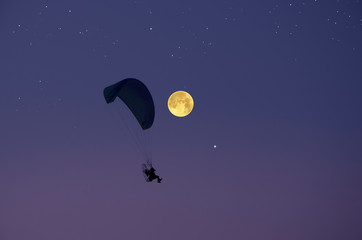Parachute and full moon in starry sky in the evening