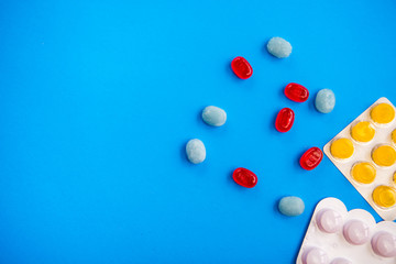 Flat lay composition with bunch of different colorful pills and blister packs in the corner. Pile...