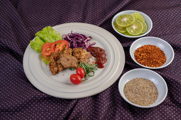 Spicy pork salad with galangal, pepper, tomato, lemon, lime, garlic and salad. Dish on a white ground on a cement floor.