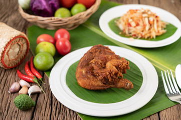 Chicken thighs fried on banana leaves on a white plate
